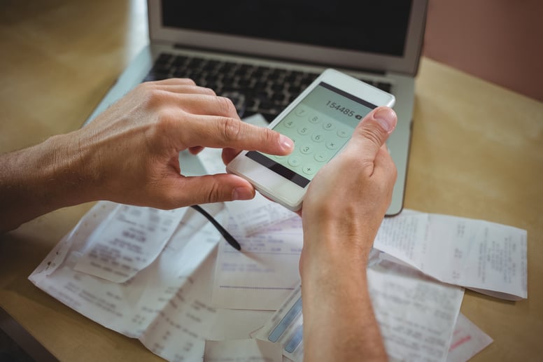 Mid section of man calculating bills on mobile phone.jpeg